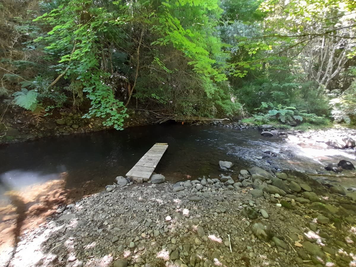 Río Chesque con muelle de madera y playa de piedras